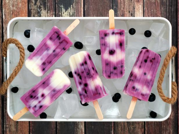 Group of blueberry vanilla ice pops in a vintage ice tray with rustic wood background