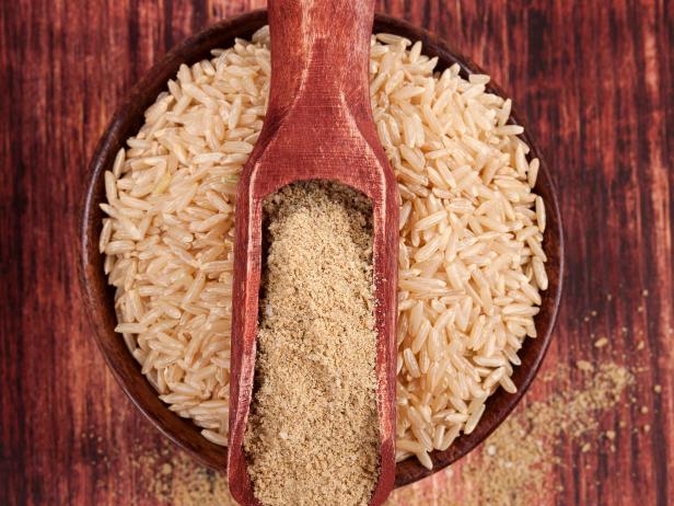 Dietary fiber. Rice in round wooden bowl with dietary rice fiber on dark brown wooden background, top view. Healthy eating concept. 
