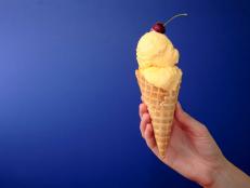 French Vanilla Ice Cream Cone with Cherry on Blue with Space for Copy