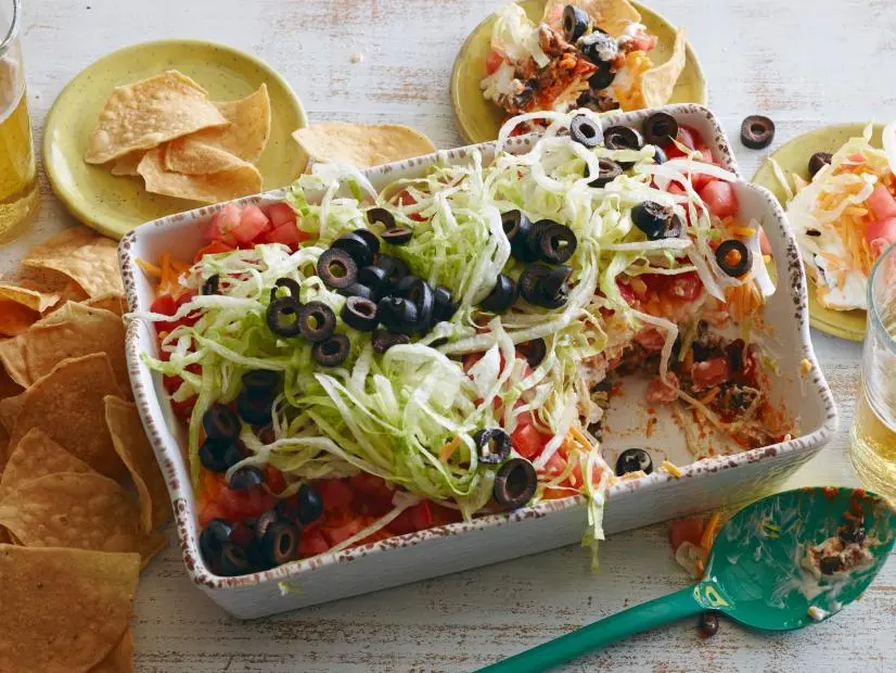 FNK TACO DIP **Game Day/Super Bowl
Food Network Kitchen
Food Network
Vegetable Oil, Ground Beef, Taco Seasoning, Tomato Paste, Black Beans, Sour Cream,
Shredded Sharp Cheddar Cheese, Tomato, Iceberg Lettuce, Black Olives, Pickled Jalapenos,
Tortilla Chips