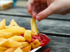 child dipping a chip into tomato sauce