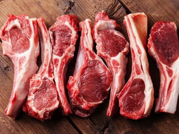 Raw fresh lamb ribs on wooden cutting board on dark background