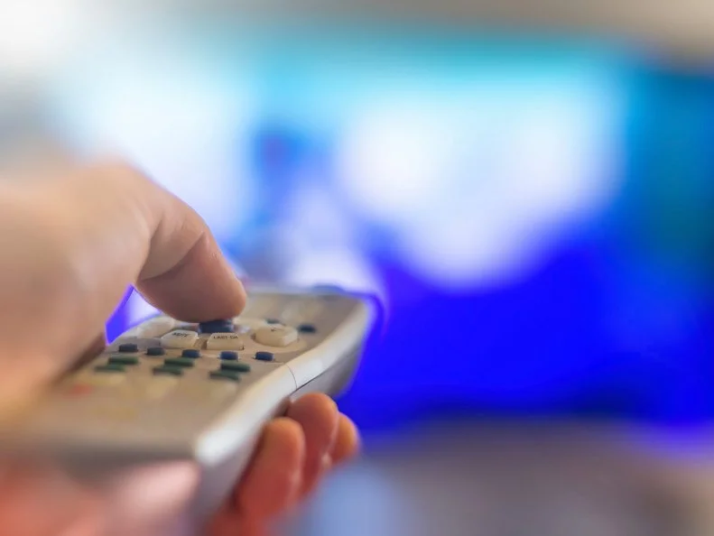 Close up of remote in hand with shallow depth of field during television watching