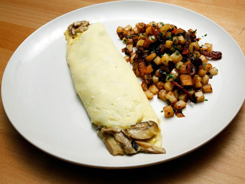 Mentor Anne Burrell's French Omelette with Mushrooms and Goat Cheese and Potato Hash with Bacon dish is displayed, as seen on Food Network's Worst Cooks in America, Season 10.