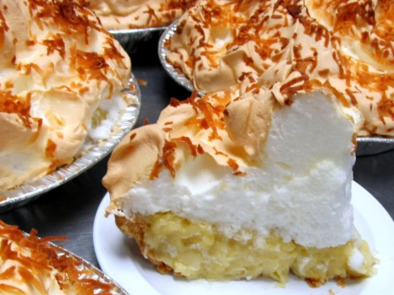 Coconut meringue pie slice amid pies on counter at Charlotte's Eats and Sweets in Keo, Arkansas as included in Arkansas's Most Iconic Eats for FoodNetwork.com