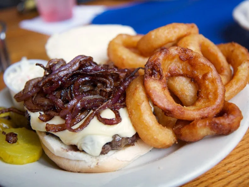 The Black Duck Cafe has served burgers and seafood from a retired barge on Westport’s Saugatuck River since 1978. The uneven floor and weathered nautical vibe lend a seaside dive bar patina that is beloved by its regulars and a curiosity to all who drive by. In-season, whole belly clams are excellent, but the Black Duck Burger is the restaurant’s year-round specialty. Sauteed peppers, onions and mushrooms smother a 6-ounce Angus burger patty — available in a 3/4-pound size for heartier appetites. The Black Duck’s character and burger prowess make it a Connecticut culinary landmark.