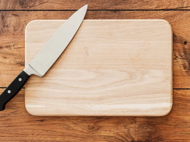 Ready to cook. Close-up top view of wooden cutting board and knife laying on it