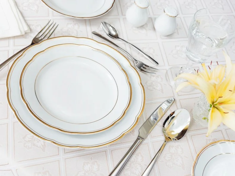Beautifully decorated table with white plates, crystal glasses, cutlery and flowers on luxurious tablecloths