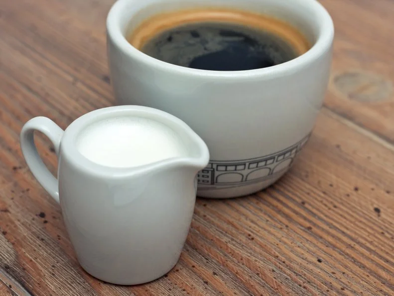 cup coffee with milk jug  on a wooden desk