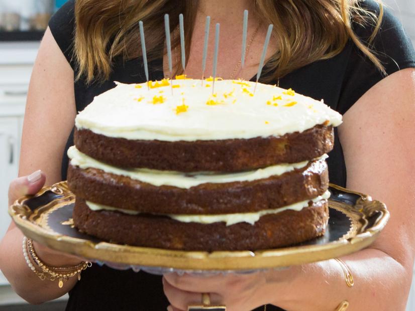 Host Tiffani Amber Thiessen poses for a picture with her ready to eat Naked Carrot Cake during Brady's Birthday Bash, as seen on Cooking Channel's Dinner at Tiffani's, Season 2.