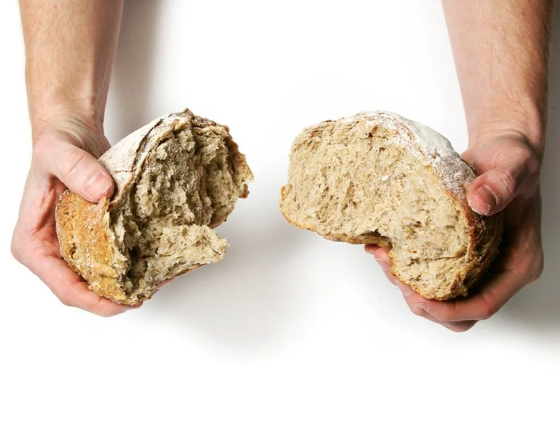 Breaking apart a fresh loaf of bread against a white background.