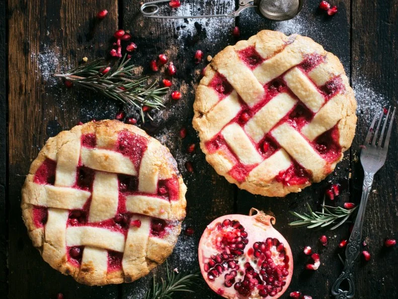 Homemade mini tart cakes with pomegranate on wooden background
