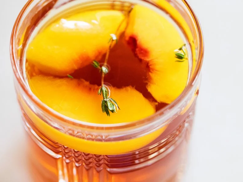 Lipton iced tea with frozen peaches instead of ice cubes and a sprig of thyme