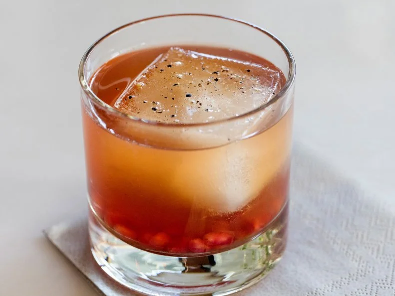 Whisky cocktail made with muddled pomegranite seeds, iced tea and pepper