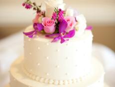 Tiered layered white wedding cake with pink and white roses and purple orchids. Converted from 14-bit RAW file.
