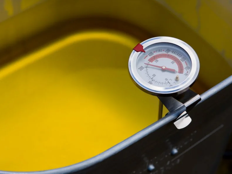 "Close up of a cooking thermometer in an outdoor home deep fryer pot heating up. Currently at about 310 degrees  Fahrenheit, not yet boiling, so the oil is a smooth, rich, deep yellow.  Lot's of copy space.More Like This:"