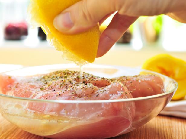 Marinating raw chicken breasts in lemon juice and herbs