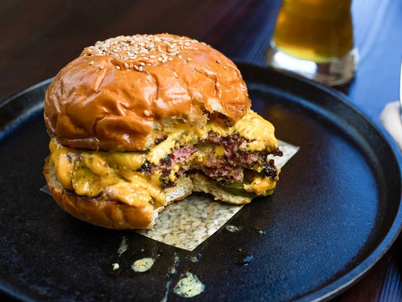 Chef Sean Brock is like the unofficial porcine king of the U.S. In the vein of Southern traditions, he infuses porky flavor into all manner of dishes. The most-talked-about item is the Husk Cheeseburger. Chuck, flank steak and Benton’s hickory-smoked bacon are ground, then formed into patties. Each one is seared in a scorching cast-iron skillet, then topped with shaved white onions and American cheese. After about 30 seconds, in which the onions warm and the cheese melts, the patty is pulled off the heat; it's then placed on a toasted and housemade buttermilk-sesame bun and topped with bread-and-butter pickles and Brock’s special sauce, a mix of ketchup, mustard, mayo, pickles and jalapenos.