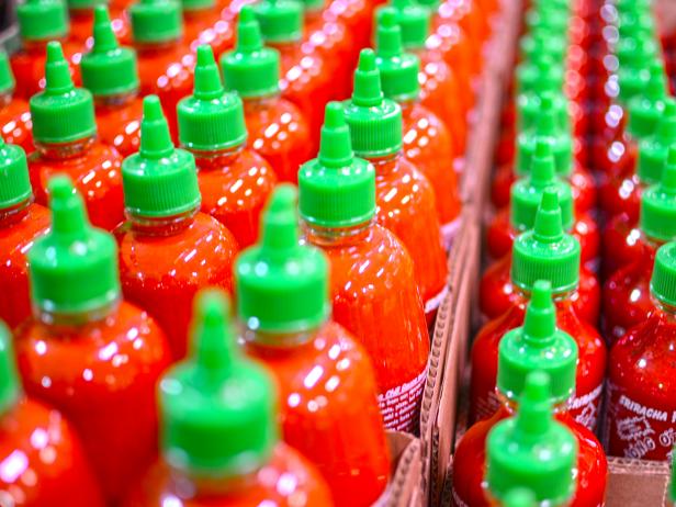 Haltom City, Texas, United States - February 20, 2015: A lot of Huy Fong's Rooster brand Thai hot sauce.  The bright red bottle, with green cap, lined up and ready to take on the world, one bottle at a time.  An American's favorite hot sauce.
