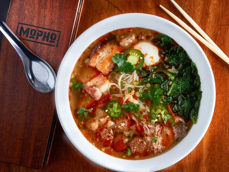 First things first: The pho at Chef Michael Gulotta’s restaurant is not at all authentic. Nor does it pretend to be. But it is rich and bright, hefty with dark, deep flavors, whether you choose beef, chicken or vegetable broth. The sandwiches, a cross between banh mi and po’ boys, are equally inauthentically enticing=. Gulotta and his crew are a curious bunch. Sometimes there are South Indian pancakes on the menu well worth a try. There’s a rotating daily special for each day of the week, and you will do right by choosing it. Vindaloo fried chicken with coconut waffles on Tuesdays; cochon de lait on Saturdays. Every day is a winner at Mopho. 