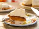 Side shot of a slice of Chocolate Marshmallow Pumpkin Pie on plate with fork, another slice, pie and cake slice in background