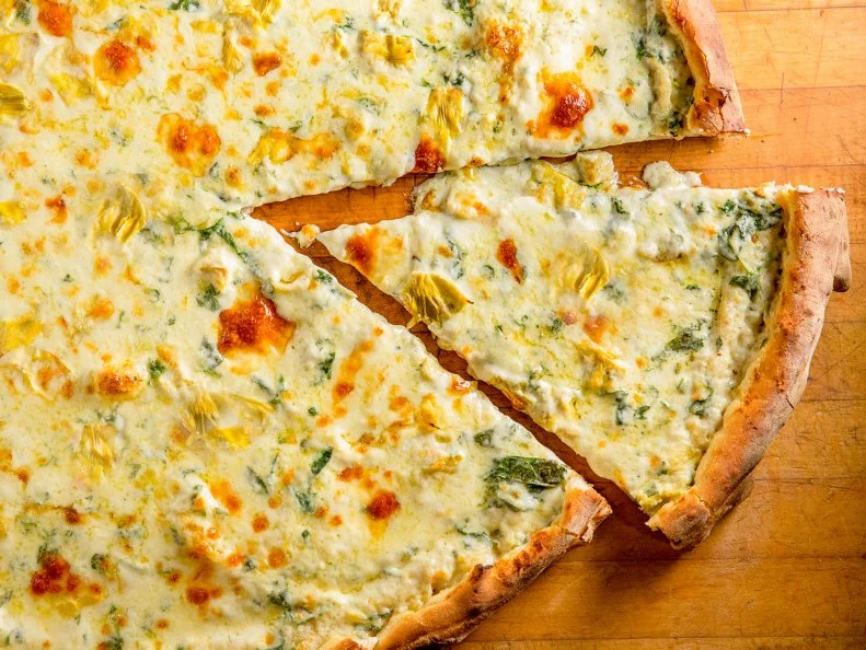 When New Yorkers want to get combine a favorite snack dip with their pizza, they head to Artichoke Basille’s. Its eponymous slice is piled about an inch high with artichoke hearts, spinach, mozzarella, Pecorino Romano and a healthy layer of butter and cream atop an extra-thick crust. On the slightly lighter side, the classic Margherita still weighs twice as much as your average NY slice. A thick and chewy crust is slathered with bright tomato sauce, aged mozzarella, Parmigiano Reggiano, fresh basil and an extra sprinkling of Pecorino. On weekend nights from about 11 p.m. to 3 a.m., lines of hungry fans snake out the door and down the block.