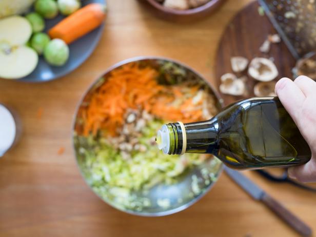 Pouring olive oil from bottle onto cabbage and carrot salad. Selective focus