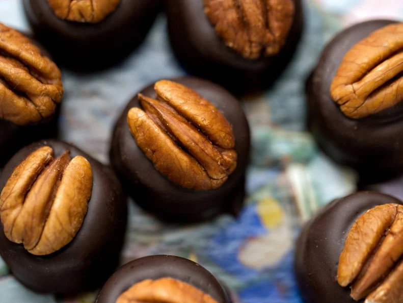 During the winter holidays and Derby week in early May, home cooks often make bourbon balls with moist centers that include crushed vanilla cookies, somewhat like European rum balls. Several excellent Kentucky artisanal candy companies produce truffle-like versions of these beloved candies: creamy, bourbon-soaked fondant centers dipped in fine chocolate. At 95-year-old Ruth Hunt Candies in Mt. Sterling, staff members top each Woodford Reserve Bourbon Ball with a perfect pecan half. The official candy maker for the Kentucky Derby, Ruth Hunt also lures thousands of fans with its distinctive Blue Monday candy bar, a chocolate-coated slice of pulled, meltaway vanilla cream candy, honoring a traveling minister who said he needed a little sweet each week to help him through his “Blue Monday.”  