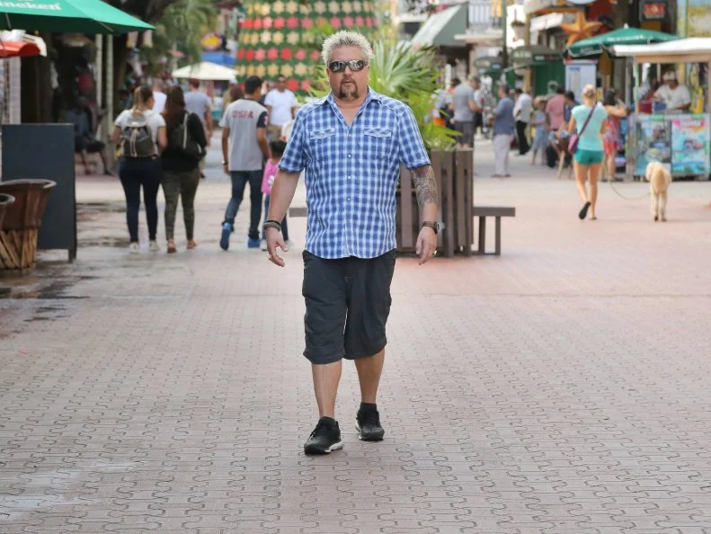 Host Guy Fieri outside Guy Fieri's Playa Del Carmen Kitchen and Bar in Centro, Playa Del Carmen, Mexico as seen on Food Network's Diners, Drive-Ins and Dives episode 2606.