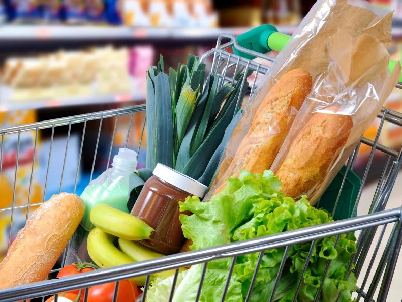 Shopping cart full of food in the supermarket aisle. Side view. Horizontal composition
