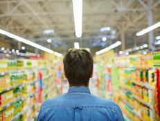 Rear view of man walking along aisle of supermarket
