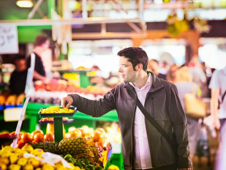 Handsome man sampling pineapples at the market.