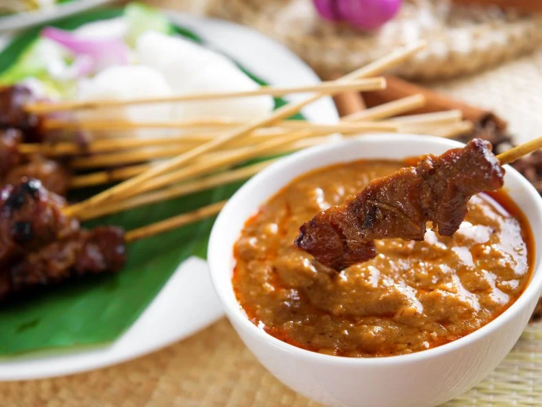 Satay or sate, skewered and grilled meat, served with peanut sauce, cucumber and ketupat. Traditional Malay food. Malaysian dish, Asian cuisine.