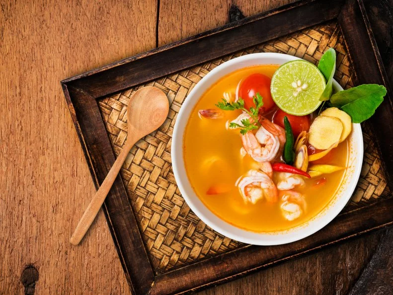Tom yam kong or Tom yum, Tom yam is a spicy clear soup typical in Thailand and No.1 Thai Dish Cuisine. Tom yam kong on wooden table. Thai food.