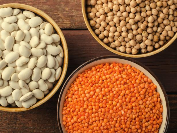 Assorted beans in bowls with red lentil, chick-pea and kidney bean on wooden background. Horizontal, toned