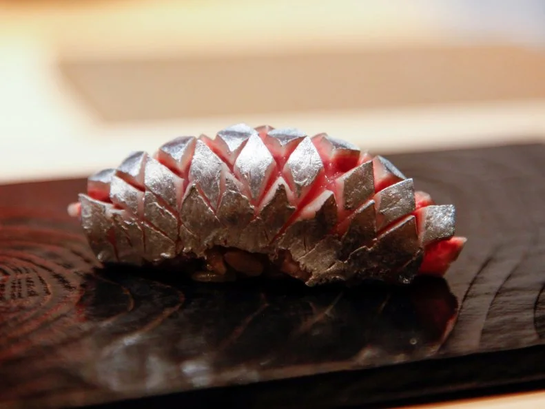 Tuna is a house specialty at Sushi Tokami, where dinner opens with a cone-shaped hand roll filled with buttery chopped tuna collar. Chef Hideyuki Sato procures his ruby fish from one of Tsukiji market’s most-famous suppliers. The ¥18,000 omakase tasting menu includes a trio of different tuna cuts, which range from lean to richly marbled, as well as an array of seasonal favorites like autumn saury, its silver skin carefully scored to reveal rosy pink flesh. Sato uses naturally fermented red rice vinegar, which lends the sushi rice an assertive tang.