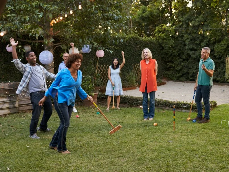 Group Of Mature Friends Playing Croquet In Backyard Together