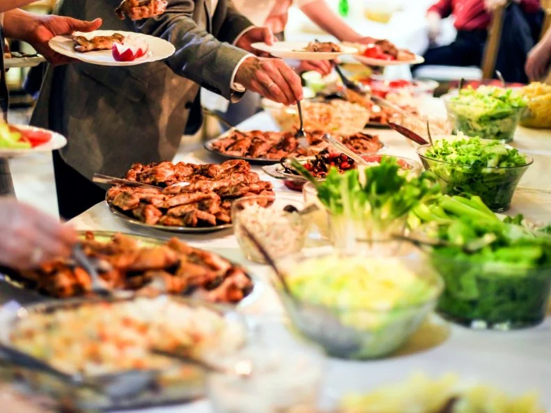 Group of unrecognizable people picking food from a buffet