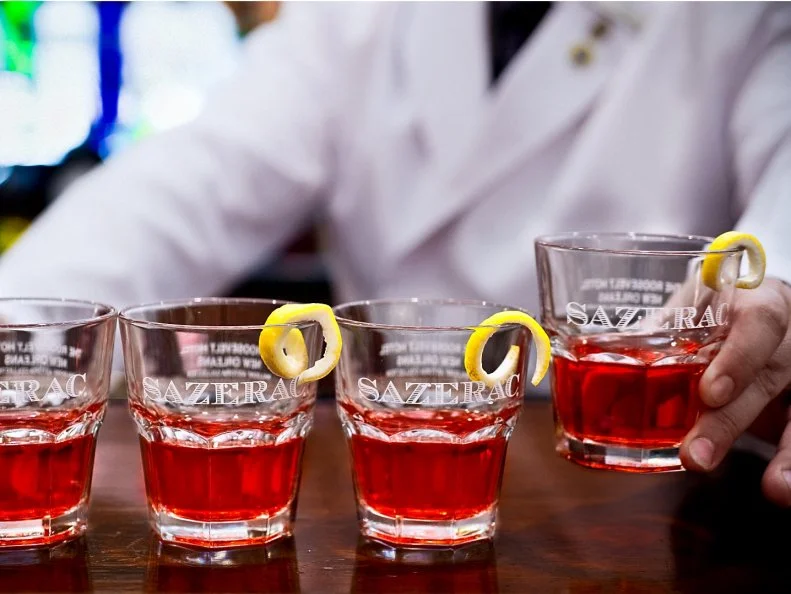 New Orleans may be world-famous for its Mardi Gras celebration, but its biggest claim to fame is that it's the birthplace of the modern cocktail. The official pick-me-up of the city is the Sazerac, reported by historical sources as America's very first cocktail. Who and where it was invented has been disputed, though many believe it was during the 1800s at Antoine AmÃ©dÃ©e Peychaud's pharmacy on Royal Street. The one thing that is not debated is the preparation: Muddle a cube of sugar with water in an old-fashioned glass, add rye whiskey, Peychaud's bitters and Angostura bitters, then stir and strain into a second old-fashioned glass lightly coated with absinthe, and finally garnish with a lemon twist. You can sip this ruby-red cocktail at dozens of New Orleans bars, including the eponymous Sazerac Bar inside the historic Roosevelt Hotel.