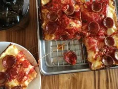 Detroit-style pizza proves that it’s hip to be square. Thick and chewy, this Motor City staple is known for its crisp, caramelized crust and distinctive shape. It may be reminiscent of Sicilian pizza, but this dish is all Detroit. Any authentic version will come slathered with deep red sauce atop a layer of melted mozzarella and brick cheeses. And the pepperoni is always tucked underneath the cheese, never on top. As for the dish’s special square shape? The pizzas are typically made in steel pans — the originals used to hold auto parts. A Motor City mainstay for at least 70 years, this Detroit-style pizza can now be found in other cities across the country — and beyond. Read on to find out where you can sink your teeth into a saucy, cheesy piece of square pie.