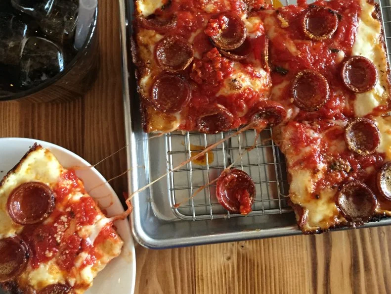 Detroit-style pizza proves that it’s hip to be square. Thick and chewy, this Motor City staple is known for its crisp, caramelized crust and distinctive shape. It may be reminiscent of Sicilian pizza, but this dish is all Detroit. Any authentic version will come slathered with deep red sauce atop a layer of melted mozzarella and brick cheeses. And the pepperoni is always tucked underneath the cheese, never on top. As for the dish’s special square shape? The pizzas are typically made in steel pans — the originals used to hold auto parts. A Motor City mainstay for at least 70 years, this Detroit-style pizza can now be found in other cities across the country — and beyond. Read on to find out where you can sink your teeth into a saucy, cheesy piece of square pie.