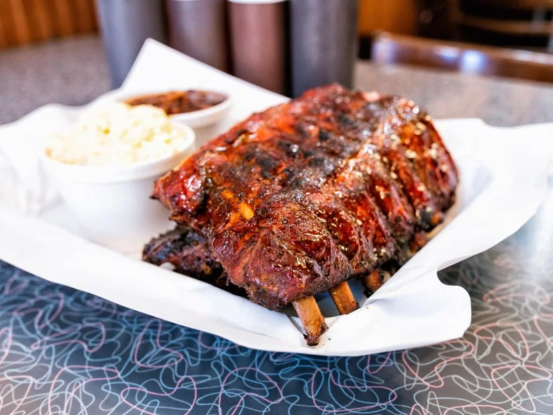 What makes the ribs at Bogart’s Smokehouse so good? It’s probably their top-secret rub. Or maybe it’s the four hours they spend sitting in the cherry wood-fueled smoker. If not those, perhaps it’s the post-smoking apricot glaze that’s brushed on, then caramelized using an industrial blowtorch. Whatever it is, it’s working. The ribs are a beautiful mix of heat and sweet, pepper and sugar. Don’t even bother with a half slab: You’ll want the whole thing.