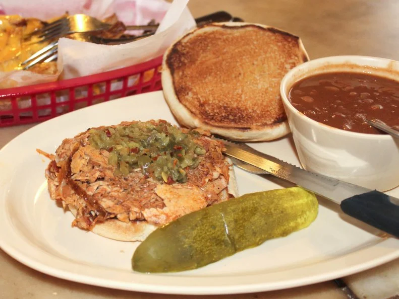Hubert Marsh brought the Juicy Pig Sandwich to Oklahoma City from Dallas in 1924. His first Pig Stand required police assistance with traffic of people queuing for the combination of pit-roasted pork drenched in stock and sour pickle relish, all stuffed in a toasted bun. In 1933, Marsh taught Bob and Helen Hammond his secrets so they could open Bob’s Pig Shop in Pauls Valley. After 44 years, they sold it to Phil Henderson, who carries on the tradition today. In Shawnee, Van’s Pig Stand has served its pig sandwich since 1930, with additional locations in Purcell, Moore and Norman.