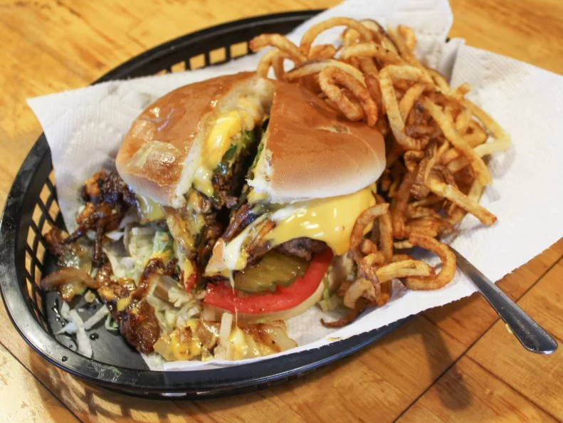 Few burger joints have drawn affection like Nic’s Grill. The home Justin “Nic” Nicholas bought in the mid-1990s had a long-dormant 22-by-22 lunch counter on the property. Rather than raze it, Nic turned the former Marcia’s Sister’s Café into a burger mecca that’s been appeared on Diners, Drive-Ins and Dives. Starting with a proprietary hamburger blend, Nic crafts huge patties that he sears on both sides, then slowly finishes in a cozy corner of his flat-top. Mounded with grilled onions, jalapenos and cheese, they arrive on a simple bun with hand-cranked curly fries. In 2016, he added Nic’s Place Diner and Lounge.