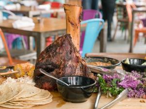 Detail: The Woodshed Smokehouse Beef Shin platter includes: 3 kale salad, fresh ricotta, roasted corn, smoked oil, borracho beans, and corn tortillas, as seen on Incredible Edible America, Season 1.