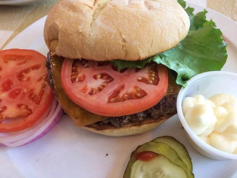 Fans will tell you there aren’t a lot of reasons to travel to the tiny town of Siler City, but that a burger from Johnson’s Drive-In is the best one there is. Leonard and Christine Johnson opened in 1946; today, their son, Claxton, is in charge. Each day Claxton selects and grinds the beef for the burgers, then shapes the thick patties. It’s a quick trip from the grill to the plate and on to the lunch counter, where hungry customers await. Regulars know to arrive early, because once the burgers sell out, folks will have to settle for a hot dog or cheese sandwich — or come back a bit earlier the next day.