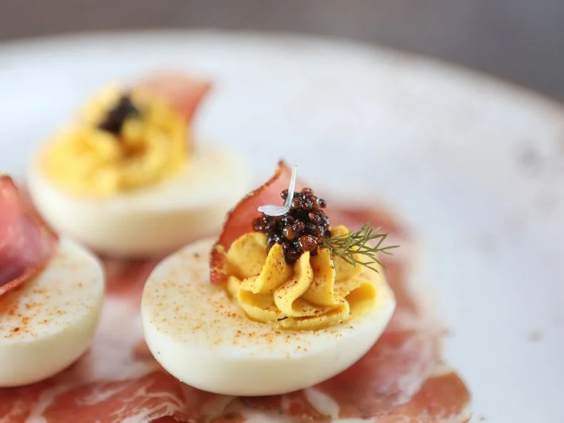 It’s no mystery that deviled eggs are typically shelled, halved and filled with a mixture made from the yolks, mayonnaise and mustard. That mix is a canvas for creative chefs. Staying true to its devilish name, Bacon Bros. Public House in Greenville starts with the freshest golden-yolked eggs, mixes them with Duke’s (of course), yellow mustard, homemade hot sauce and a touch of vinegar. Their Devil’s Dust Eggs are then topped with spicy tasso ham, tangy mustard seeds and a sprinkling of Devil’s Dust, a blend of some of the hottest peppers in the world grown and dehydrated in-house.