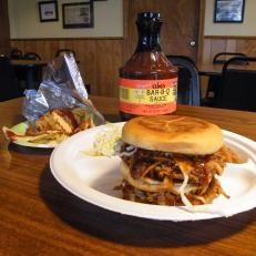 There’s plenty of barbecue in Mississippi, and most borrows from the styles that traveled downriver from Memphis and St. Louis. But Abe’s Bar-B-Q in Clarksdale has a style all its own. The pork butt isn’t pulled or shredded after smoking. It’s chilled overnight to congeal the fat, then sliced paper-thin and reheated on a griddle. The slices are chopped into slivers and doused with a tangy house barbecue sauce, then tucked into a grilled bun with a peppery oil-and-vinegar-dressed slaw rather than the mayonnaise-laden kind that typically prevails in smokehouses. Lebanese immigrant Abraham Davis learned to barbecue and roll tamales from his new neighbors before opening a tiny restaurant in 1924. Abe’s has remained a community favorite throughout its existence, and a landmark stop for travelers on the Blues Highway. 