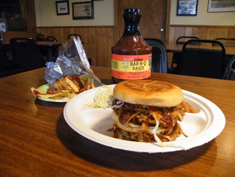 There’s plenty of barbecue in Mississippi, and most borrows from the styles that traveled downriver from Memphis and St. Louis. But Abe’s Bar-B-Q in Clarksdale has a style all its own. The pork butt isn’t pulled or shredded after smoking. It’s chilled overnight to congeal the fat, then sliced paper-thin and reheated on a griddle. The slices are chopped into slivers and doused with a tangy house barbecue sauce, then tucked into a grilled bun with a peppery oil-and-vinegar-dressed slaw rather than the mayonnaise-laden kind that typically prevails in smokehouses. Lebanese immigrant Abraham Davis learned to barbecue and roll tamales from his new neighbors before opening a tiny restaurant in 1924. Abe’s has remained a community favorite throughout its existence, and a landmark stop for travelers on the Blues Highway. 