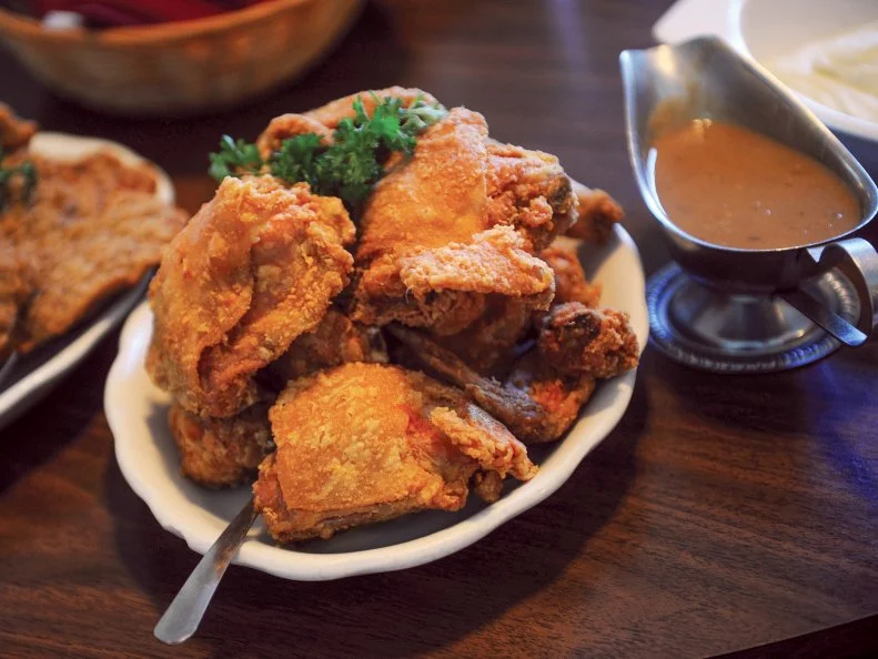 Fried chicken could well be the Mississippi state bird. It’s served in every environment, and most of it is excellent. At the Four Corners Chevron Service Station in Oxford, Ole Miss students stand up to eat deep-fried chicken on a stick after a night of drinking. In Vicksburg, the after-church crowd sits down to dine at Walnut Hills, a 19th-century antiques-furnished house where lazy Susans — a throw-back to boarding house days — groan with platters of golden birds, country-style vegetables, hot rolls and bottomless pitchers of sweet tea. Most folks enjoy socializing on the rocking chair–filled porch until their table is ready.